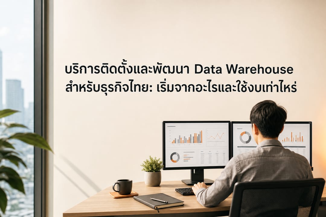 A modern Bangkok corporate office desk viewed from over the shoulder showing an analyst working on a dual-monitor setup with business dashboard charts and data tables, without showing faces or readable text